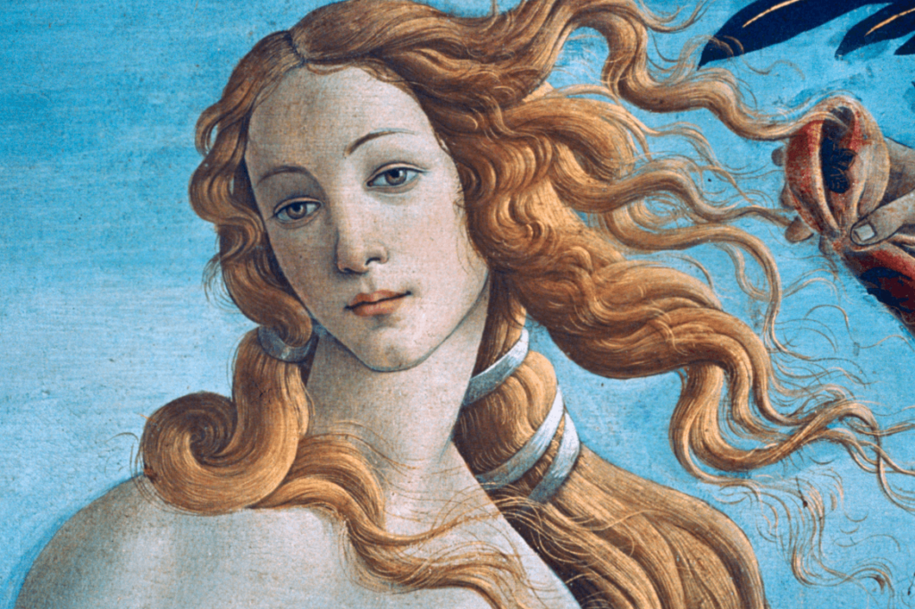 Detalhe de uma pintura clássica representando Vênus, com o retrato de uma mulher com cabelos dourados ondulados e olhar sereno sobre um fundo azul.